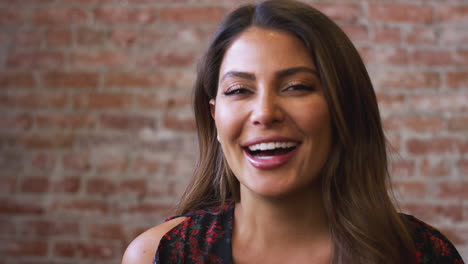 Portrait-Of-Smiling-Hispanic-Woman-Standing-Against-Brick-Wall-In-Coffee-Shop