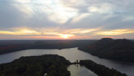 Majestuosa-Agua-De-Lago-Con-Bosque-De-Color-Otoñal-Durante-La-Puesta-De-Sol,-Vista-Aérea