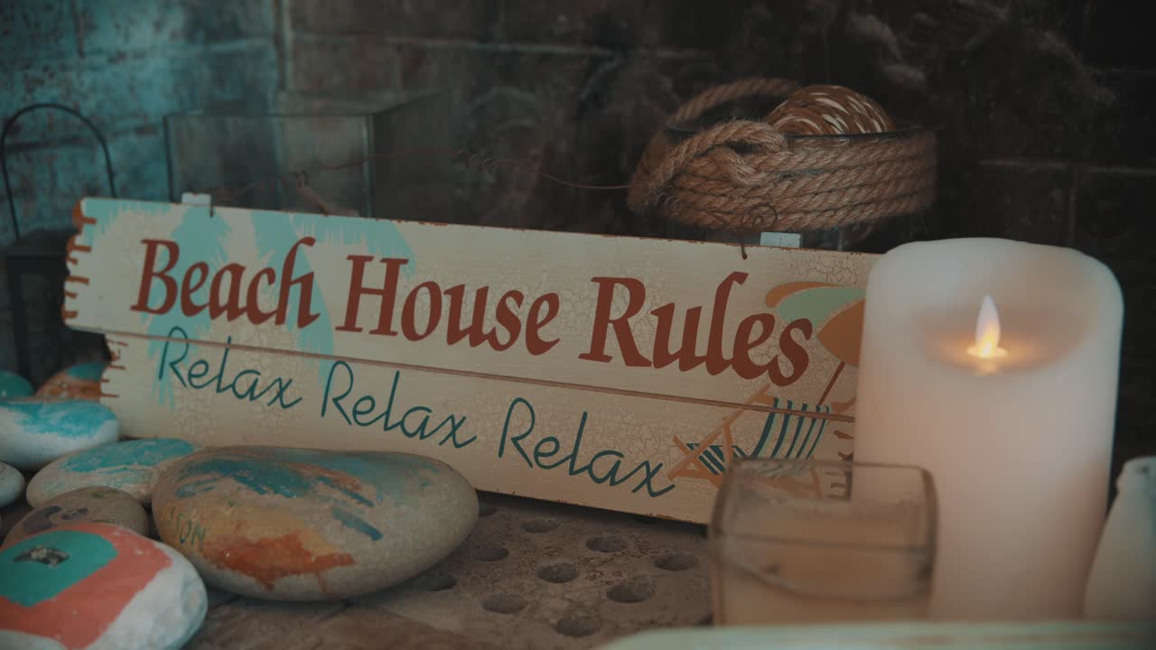 decoración interior en una chimenea con letrero de relajación, piedras pintadas, velas y cuerdas en una casa de verano en la playa.