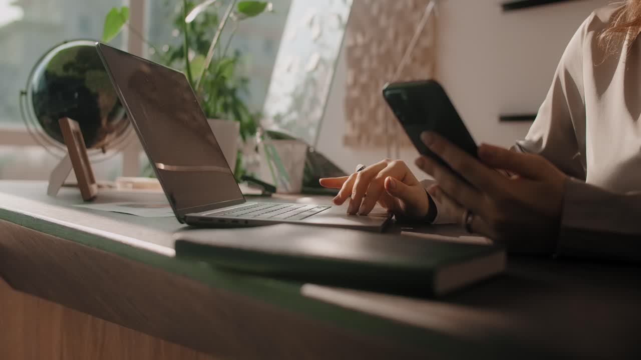 Woman working on laptop and smartphone in an office