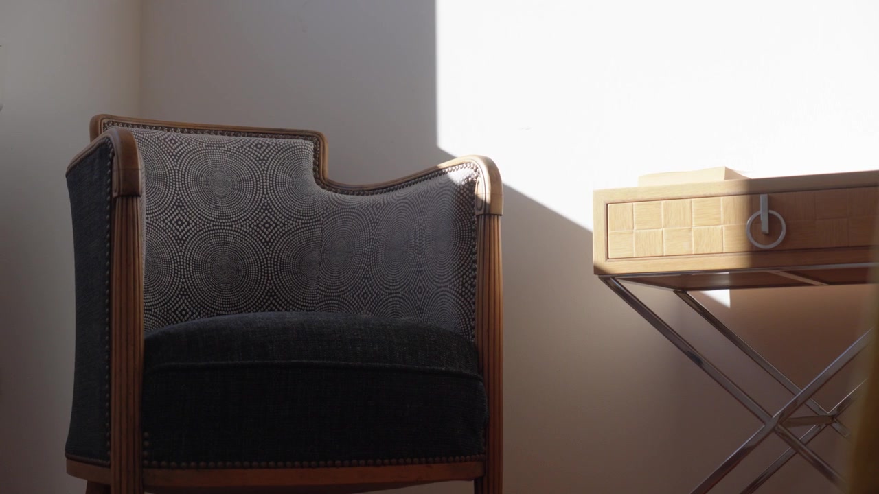 Poltrona e comodino con ombre del sole in una casa calda e minimalista, primo piano