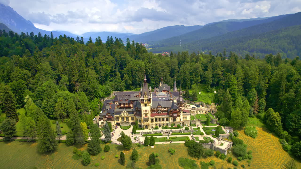 Ilmakuva dronella Romanian Peleșin linnasta. Linna puutarhoineen ja turisteineen Karpaateilla, ympärillään rehevä metsä