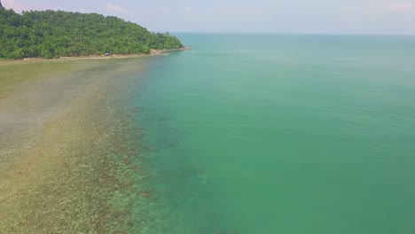 drone-panning-shot-flies-over-coral-reef-with-tropical-Island-jungle