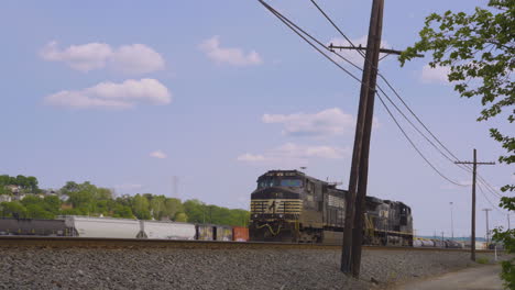 A-black-train-engine-backs-down-the-railroad-tracks-in-a-rural-area