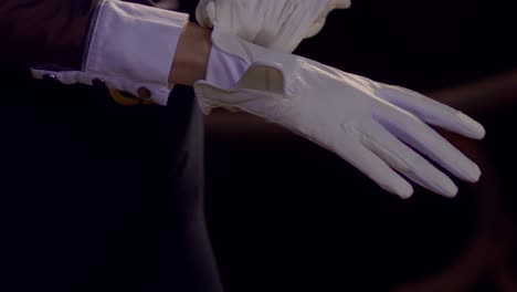 cinematic slow motion shot of a woman putting on white horse riding gloves and closing the velcro, close-up slomo