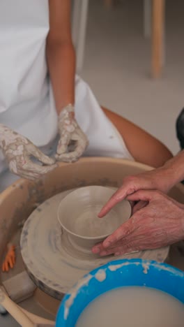 hands working on a pottery wheel shaping a clay bowl