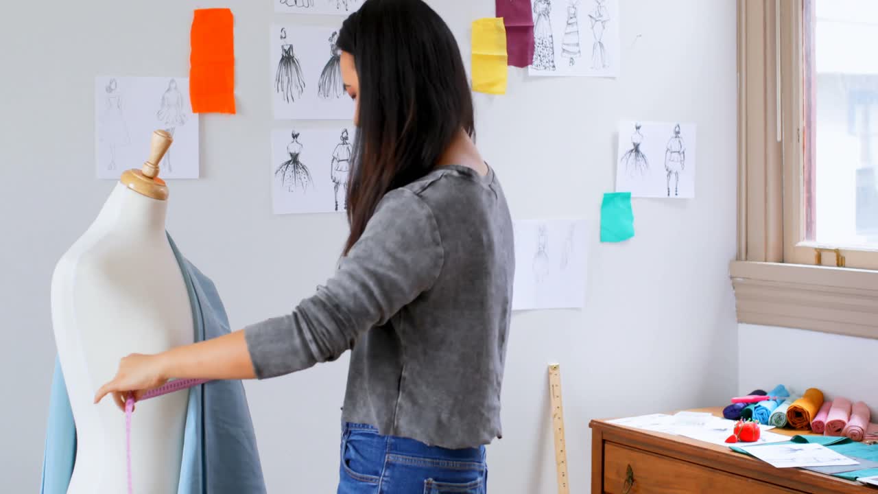 패션 디자이너가 스케치를 보고 직물을 4k로 측정합니다.