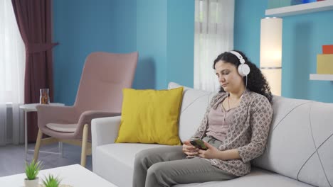 young woman listening to music with headphones is unhappy and sad.