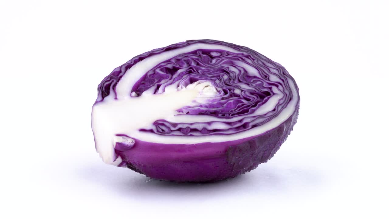 macro de sección transversal de un medio mini repollo rojo con gotas de agua. girando lentamente en la mesa giratoria aislada en el fondo blanco. primer plano.