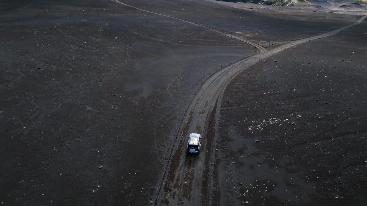 4x4 driving on barren volcanic terrain in Iceland, aerial view of dramatic wilderness and raw nature