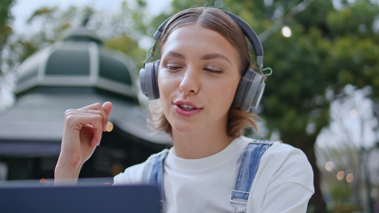 Woman enjoy friendly video call gesturing to laptop on street cafeteria closeup