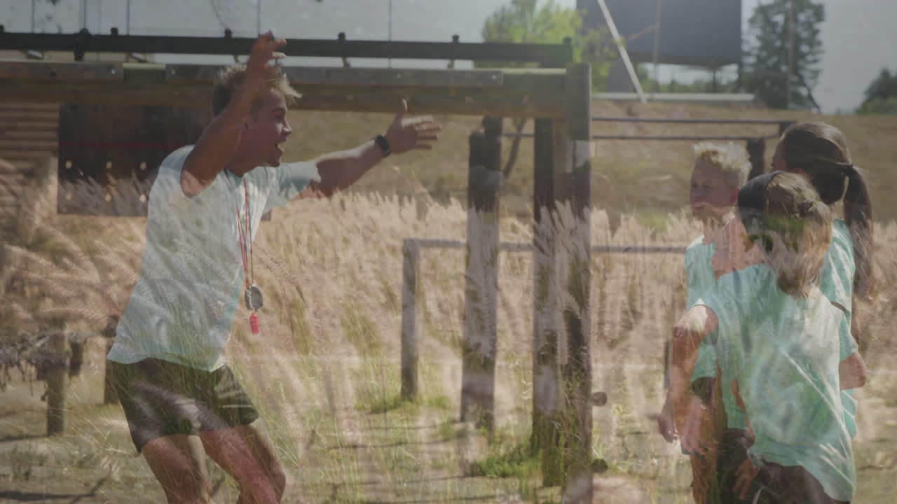 In school, coach instructing children during outdoor sports animation on grassy field
