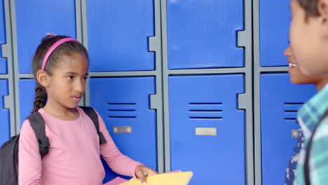 in school, three biracial children standing by blue lockers