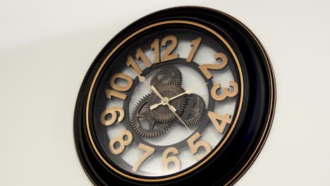 vintage design wooden wall clock with open mechanism shows ten to two, white background
