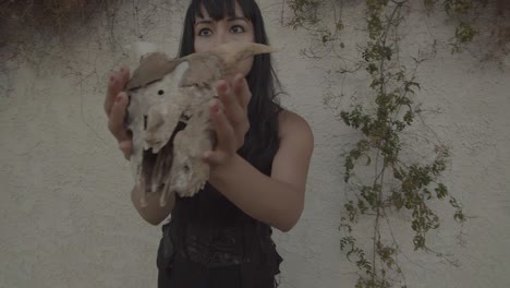 an young witch holds skull of an animal with horns