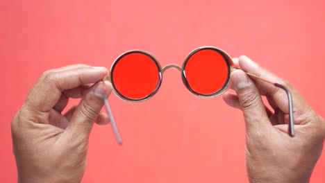 red round sunglasses in hands