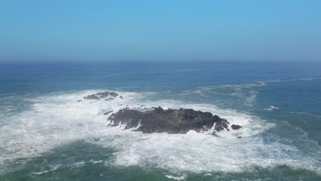 reveal drone shot of waves on a rocky beach - 4k aerial view