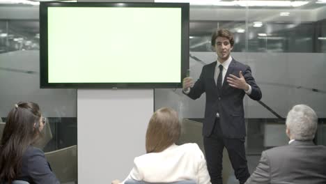 confident young speaker talking and pointing at display