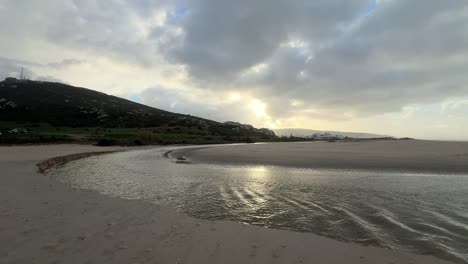 Eine-Zeitrafferaufnahme-Einer-Strandlandschaft-Zeigt,-Wie-Wasser-Sanft-Kanäle-In-Den-Sand-Gräbt-Und-Das-Konzept-Der-Erosion-Und-Der-Transformativen-Wirkungen-Der-Natur-Veranschaulicht.