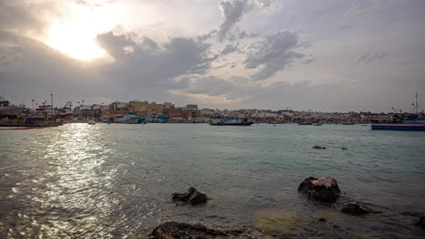 The-sun-reflects-on-the-harbor-at-Marsaxlokk,-a-fishing-village-in-Malta's-south-eastern-area