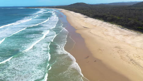 cinematic revealing drone shot of sandy beach and rock outcropping at cabarita beach australia