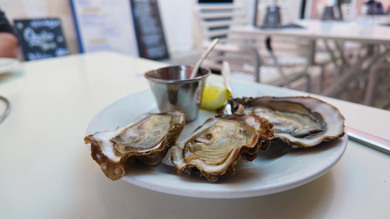 Close-up shot of fresh raw oysters with lemon and mignonette sauce on a restaurant table