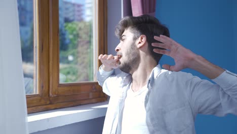 the man who opens the curtains yawns and relaxes.