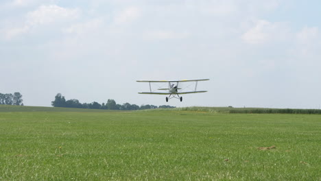 ultra light bi-plane take off and airborne on green fields in the countryside