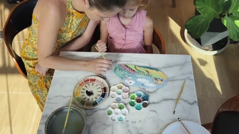 mother and daughter painting pottery together