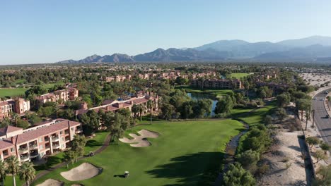 toma aérea descendente y panorámica de un brillante campo de golf en un resort de lujo en palm desert