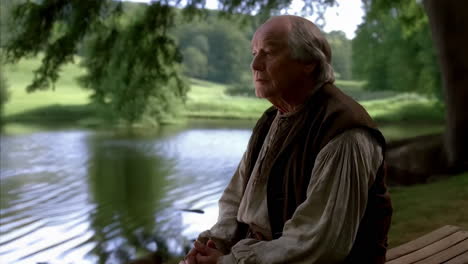 elderly man in traditional attire reflecting by a lakeside