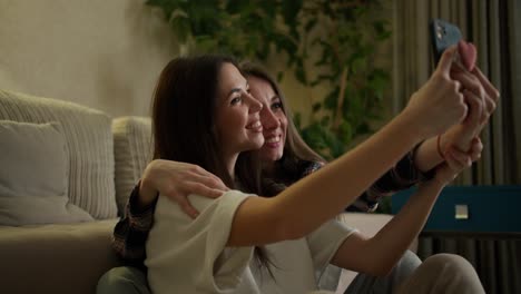 Two-women-making-selfie-by-smartphone-sitting-on-floor-at-home