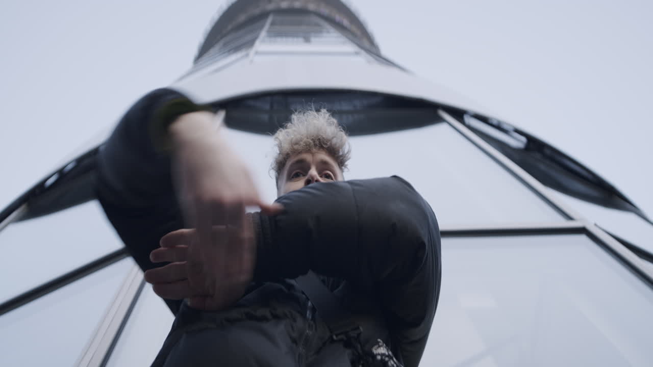 Young Man Dancing in Front of Modern Architecture