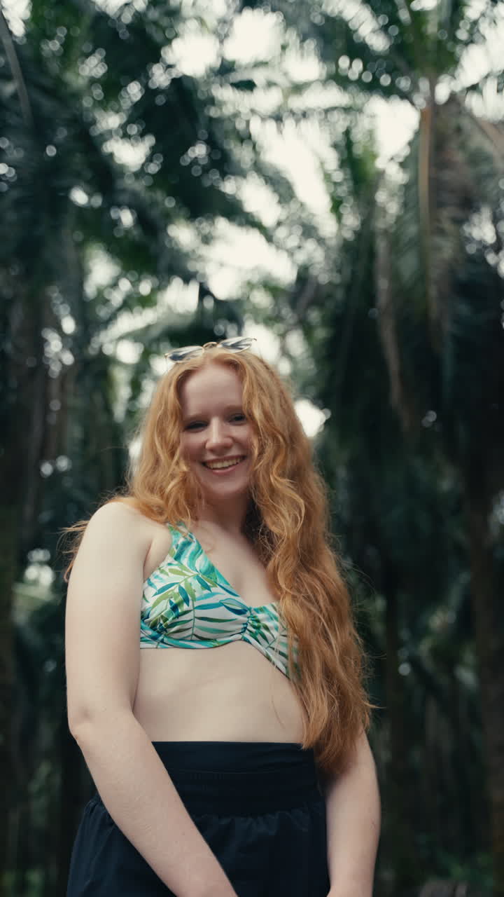 Kvinde i bikinitop smiler i skoven