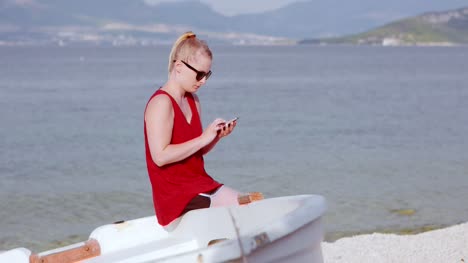 young lady sitting on beach while using her mobile device 10