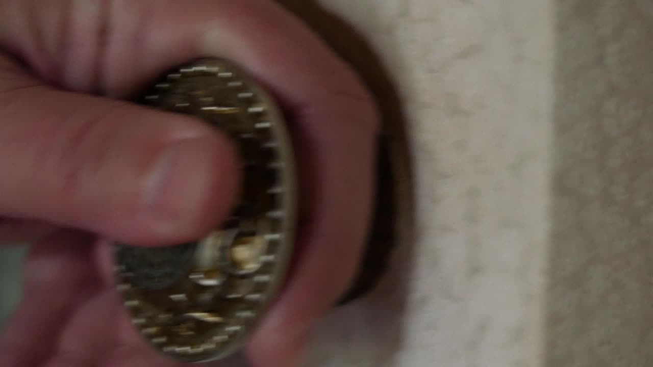 한 남자의 손이 둥근 금속 문 손잡이를 만지다. 한 남자가 칠한 나무 문을 열었다.