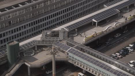 -Pedestrians-Walking-Through-Japanese-Mall-Exterior-in-Downtown-Area-of-Kokura,-Kitakyushu,-Japan-With-Cars-And-Overpass