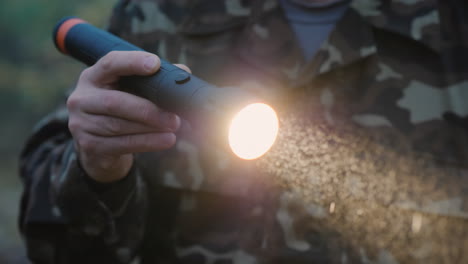 una mano con una linterna ilumina el camino en el bosque las gotas de niebla son visibles en un haz de luz