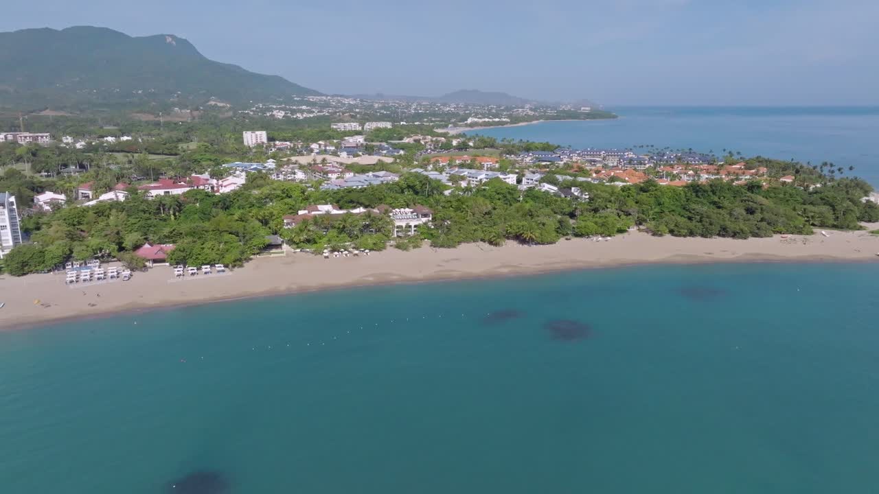 Luxury catamaran anchored on sandy beach of Playa Dorada in Puerto Plata. Sunny summer day with clear Caribbean sea water in Dominican Republic. Aerial lateral wide shot