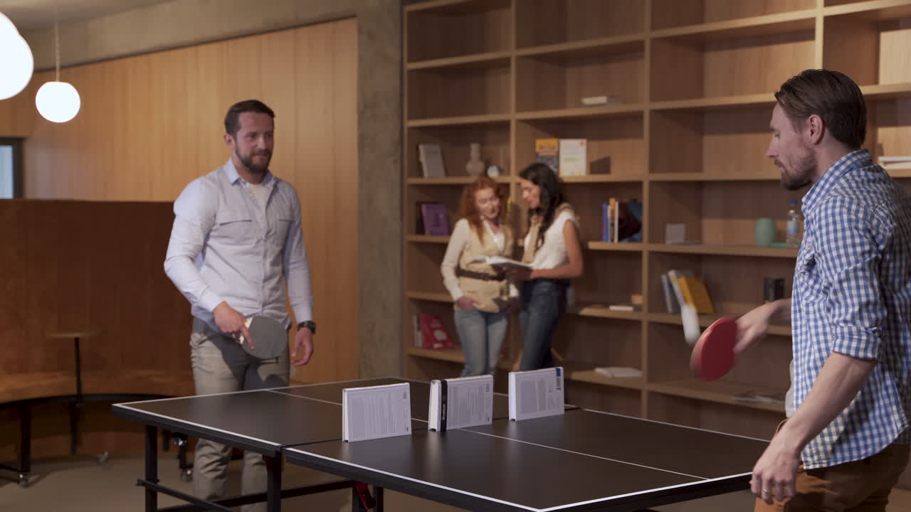 Two coworkers take a break from work by playing ping pong