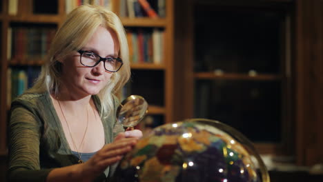 a woman looks at a beautiful globe in the library