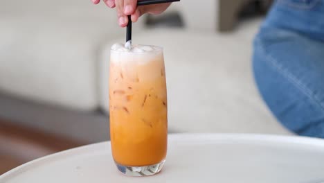 agitando un vaso alto de té helado en una mesa