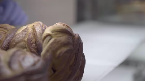 mano de trabajador en guantes poniendo pasteles recién horneados en el estante de la cafetería