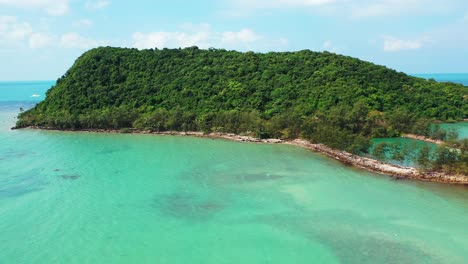 Isolated-remote-tropical-island-with-lush-vegetation-and-green-trees-forest-surrounded-by-shallow-turquoise-lagoon