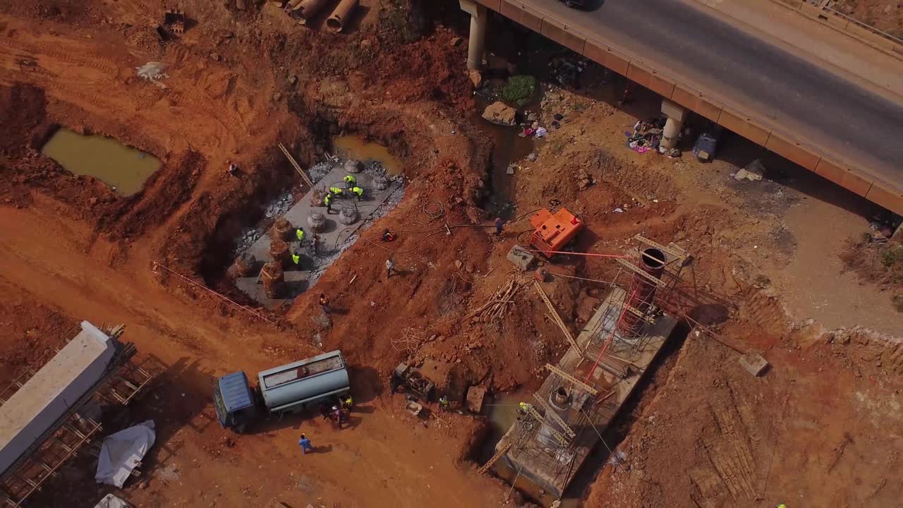 Top down aerial of workers building pillars at the construction site of a new highway in Abuja, Nigeria