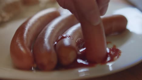 dipping a sausage in ketchup. close-up shot