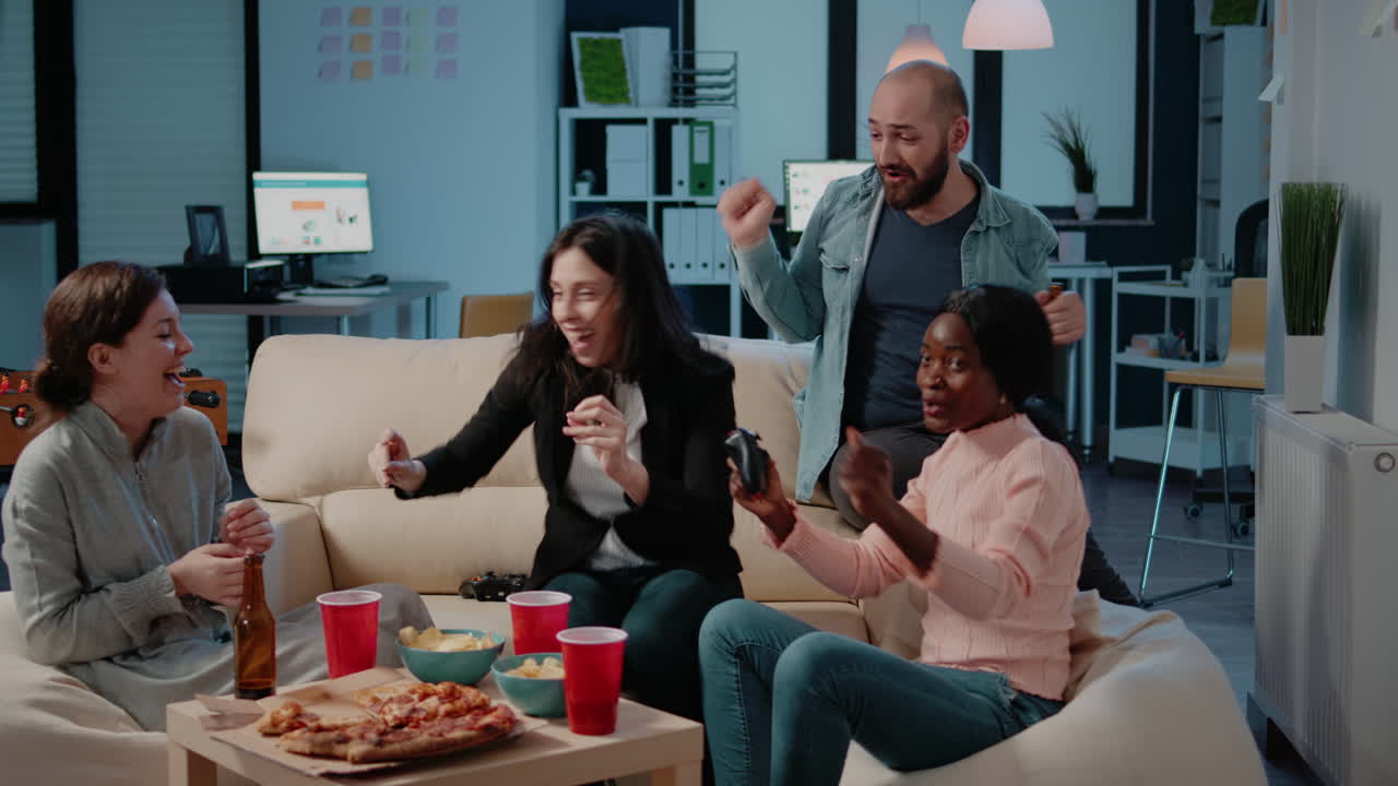 Cheerful coworkers playing video games with joysticks and console