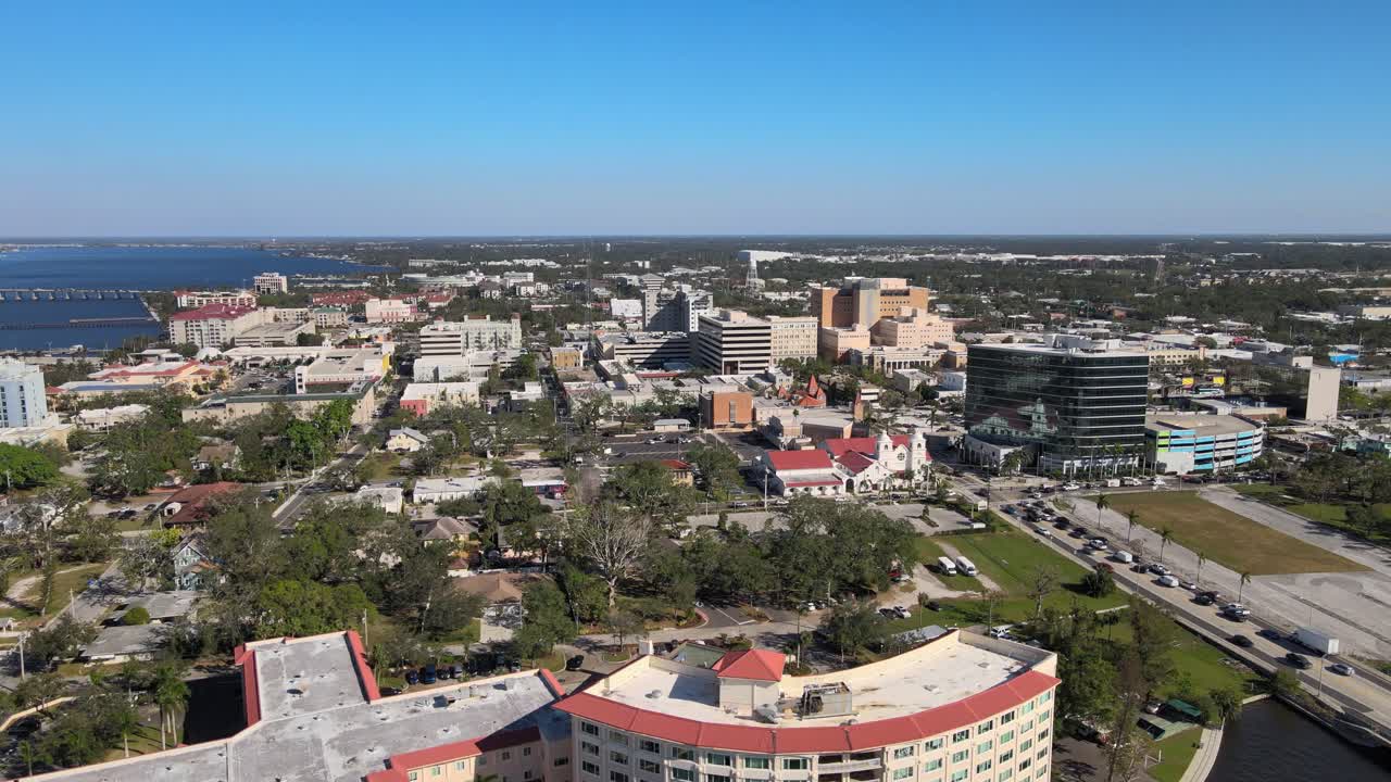Aerial drone footage of Bradenton Florida showcasing the downtown skyline, riverfront, and bridges under clear blue skies. Wide Orbit Left E