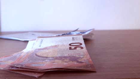 Close-up-shot-of-a-man-counting-50-euro-notes-from-his-hands-and-placing-them-on-the-table-one-by-one-in-a-white-background