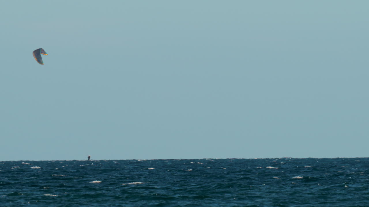 View of a lone kitesurfer riding over the waves under the golden evening light